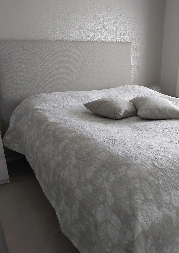 Harmaa Hiidenkivi päiväpeitto parisängyllä.
