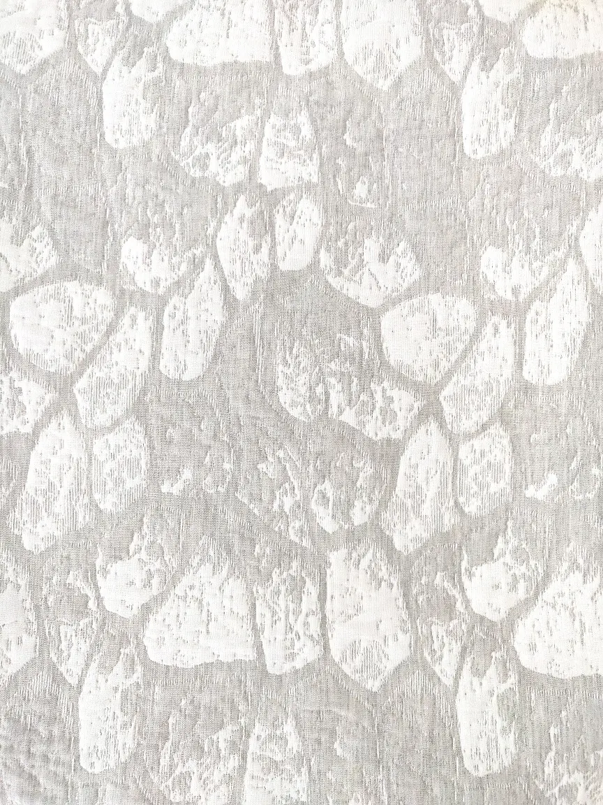 Hiidenkivi päiväpeitto kuosi harmaa. Kauniita valkoisia "kiviä" harmaalla taustalla.